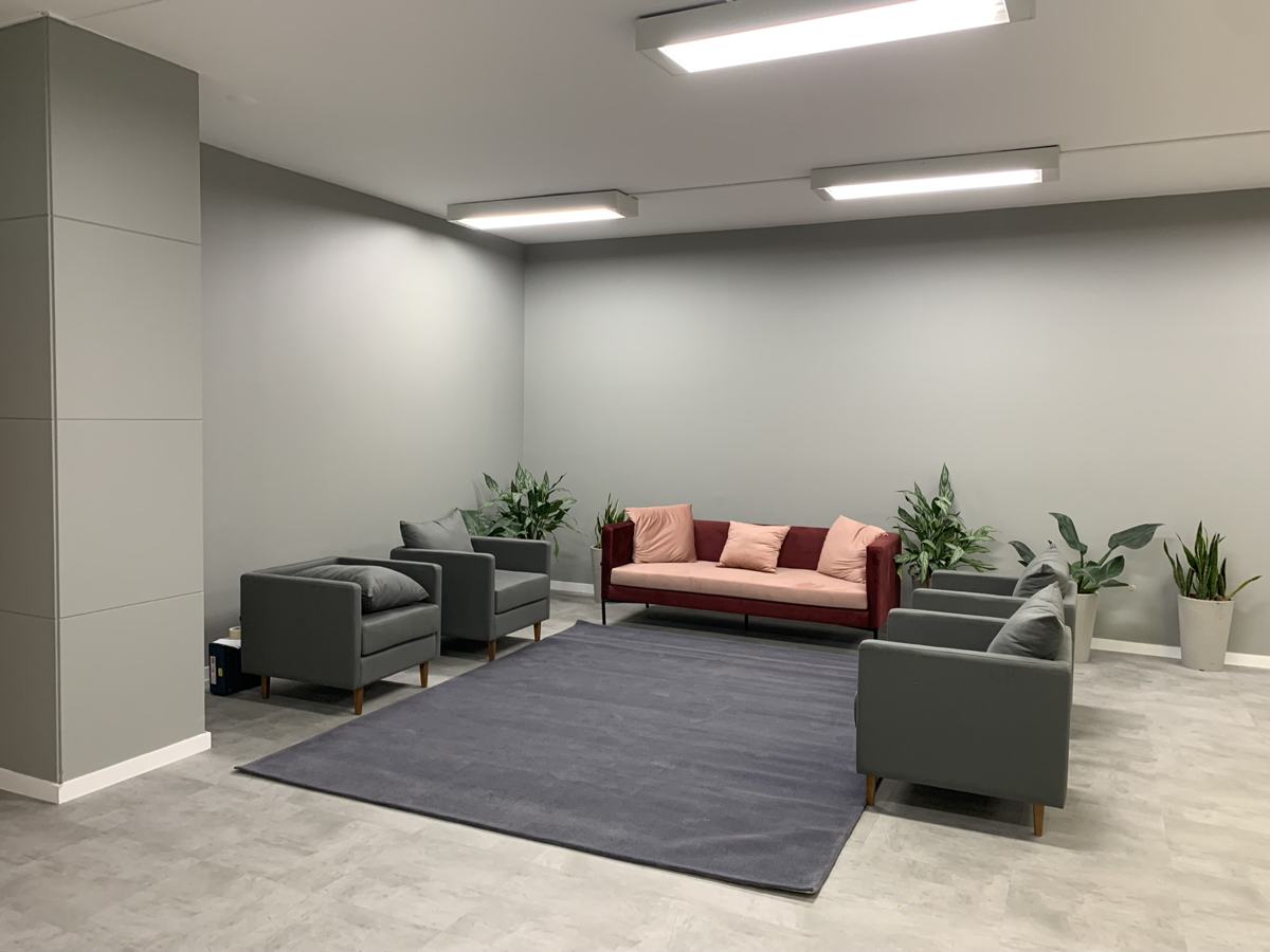 Sala de espera corporativa em Maringá com sofás cinza e tapete