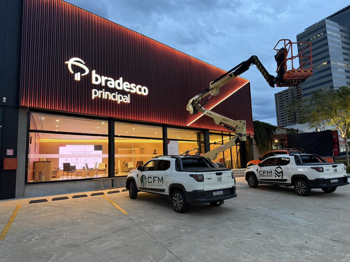 Caminhonetes da CFM Engenharia em frente à fachada iluminada de uma agência Bradesco Principal